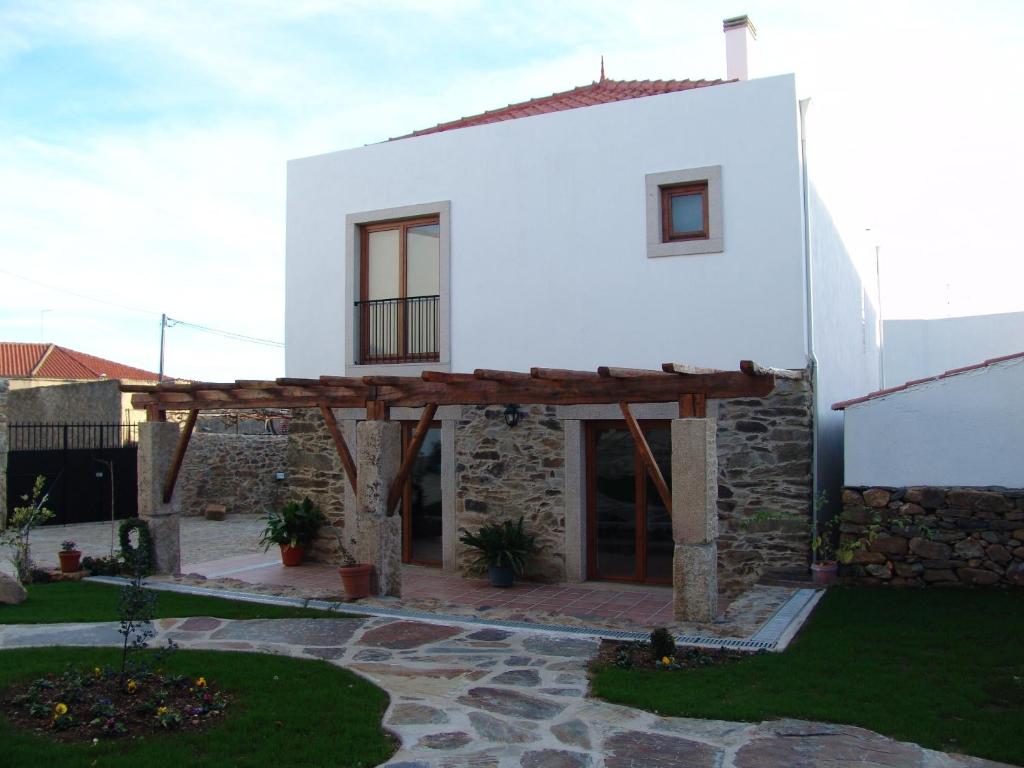 uma casa branca com telhado de madeira e um ptio em Casa Santa Catarina em Penha Garcia