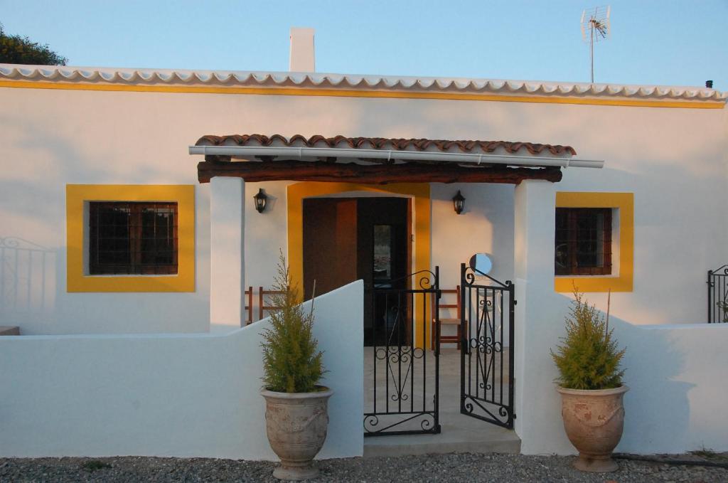 ein weißes Haus mit einem Tor und Topfpflanzen in der Unterkunft Can Jaume Guillem in Sant Carles de Peralta