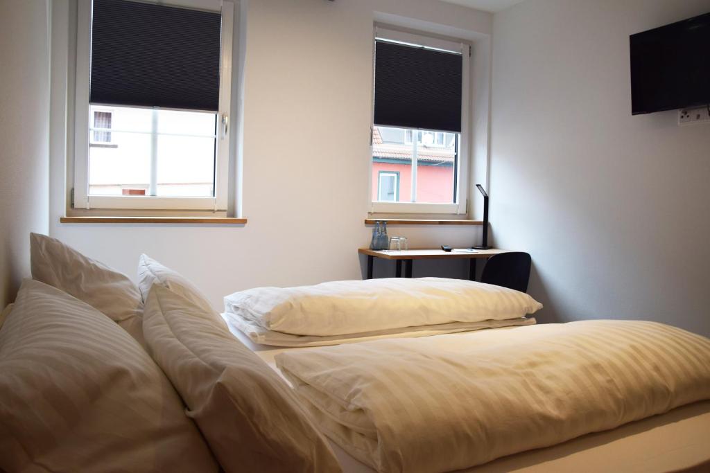 two beds in a room with two windows at Herberge Bärenschenke in Meßkirch