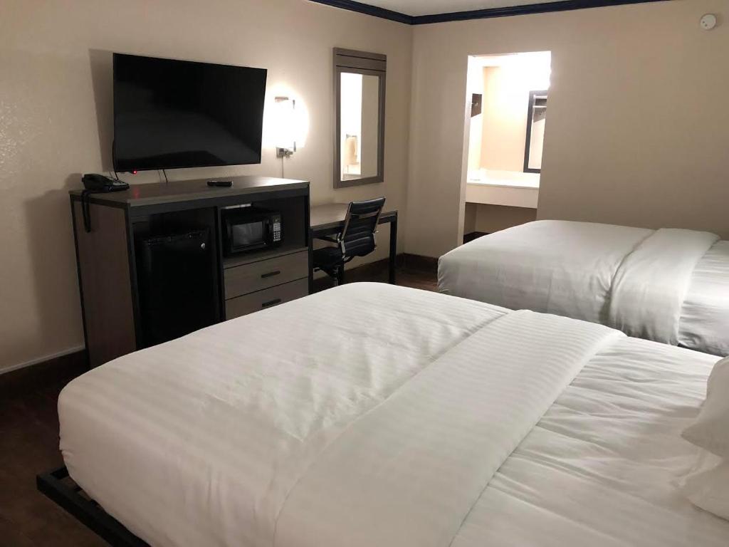 a hotel room with two beds and a flat screen tv at Travelers Inn and Suites Wharton in Wharton