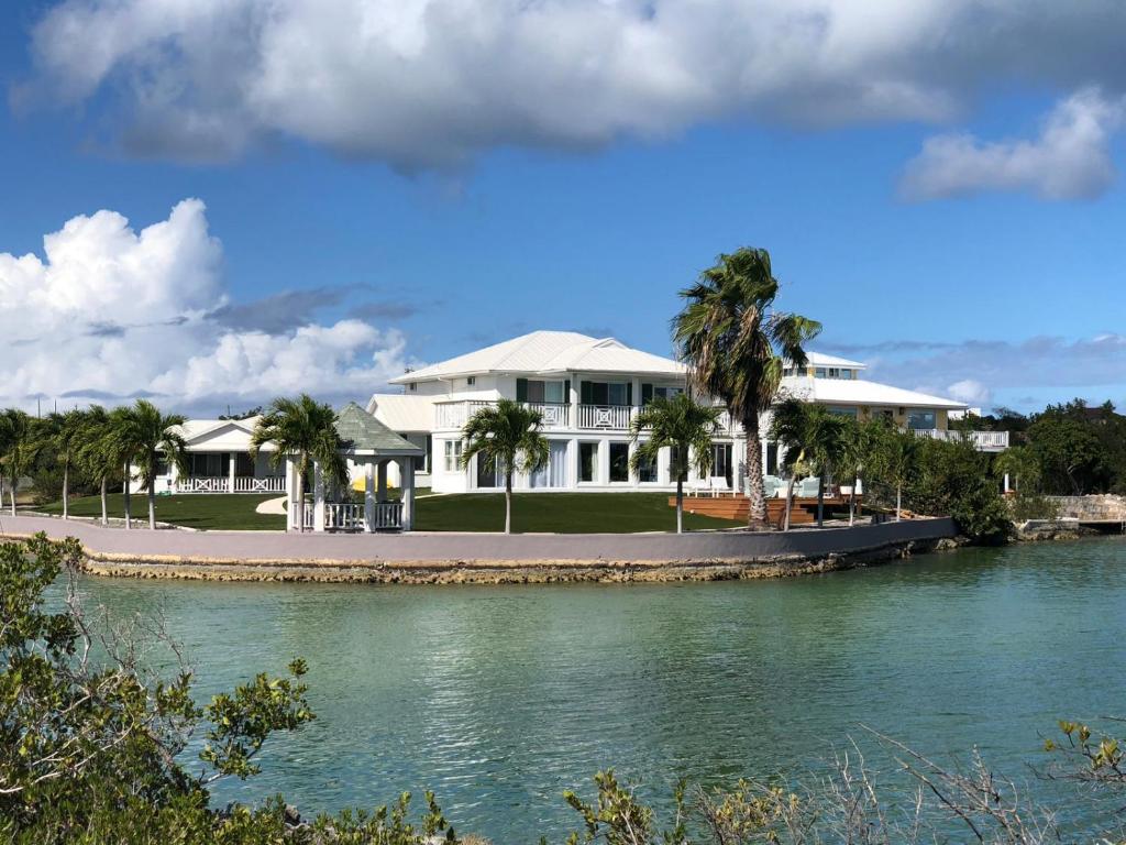 a large white house next to a body of water at Palm Point Loft in Turtle Cove