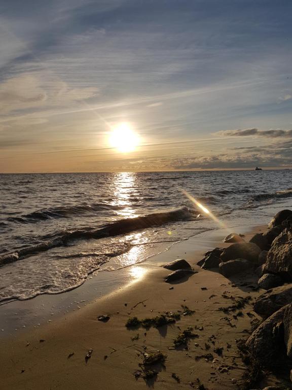 a sunset on a beach with the ocean at Baltic Beach Apartment in Mechelinki