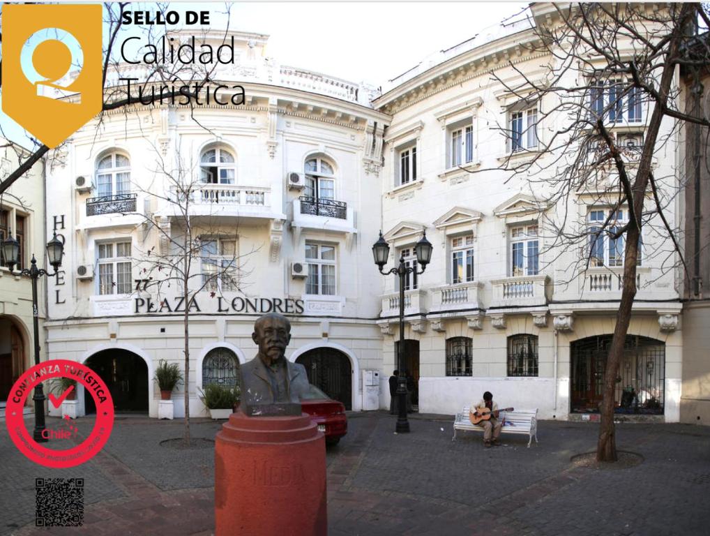 a man sitting on a bench in front of a building at Hotel Plaza Londres 77 in Santiago