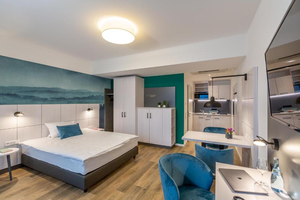 - une chambre avec un lit et deux chaises bleues dans l'établissement Boardinghouse Hirsch - Apartments in Kork, à Kehl