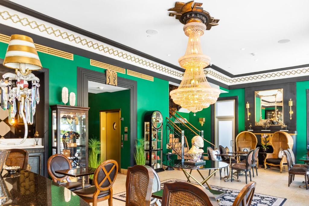 a restaurant with green walls and chairs and a chandelier at Cavalier South Beach Hotel in Miami Beach