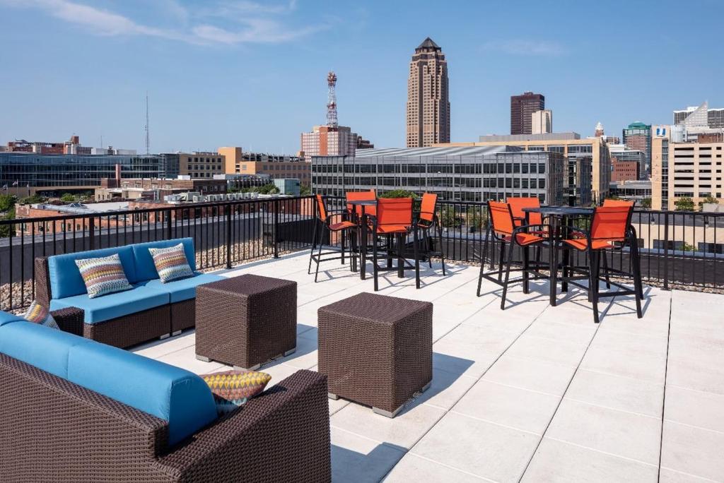 un patio en la azotea con sillas, mesas y un perfil urbano en Sleepover Premier Downtown Des Moines Apartments, en Des Moines