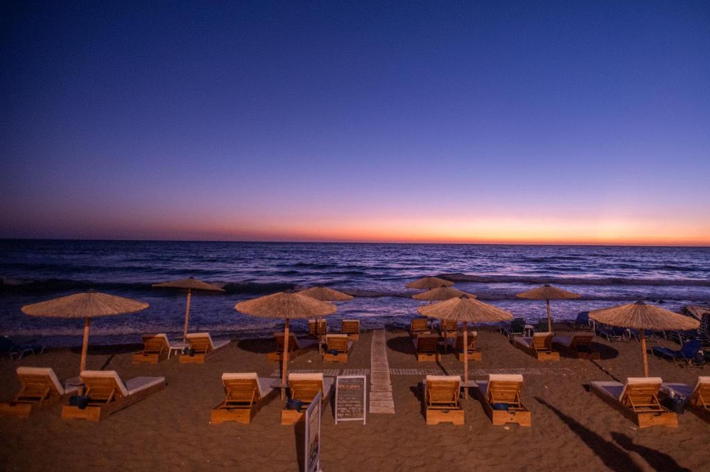 阿齊歐斯·貢多斯的住宿－Romantic Palace Beach Apartments，海滩上设有椅子和遮阳伞,还有大海