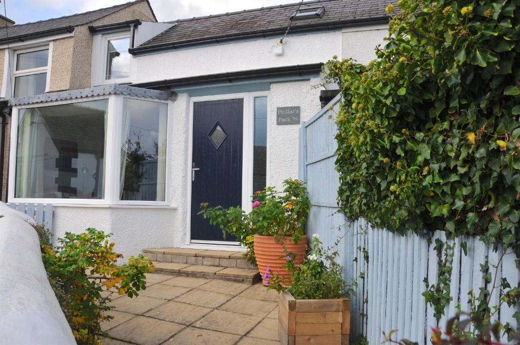 a white house with a blue door and a fence at Pedlars Pack in Moelfre