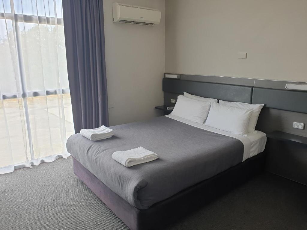 a bedroom with a bed with two towels on it at Prospect Hotel Motel in Blacktown