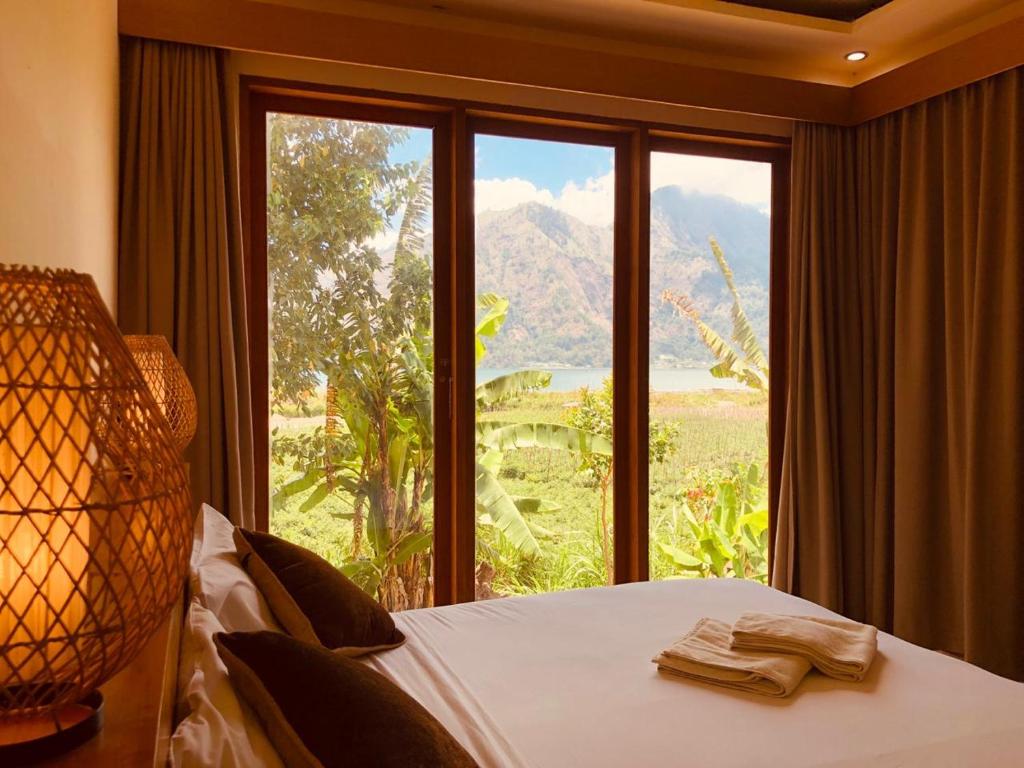 a bedroom with a bed and a large window at Segara Healing Villa in Kintamani
