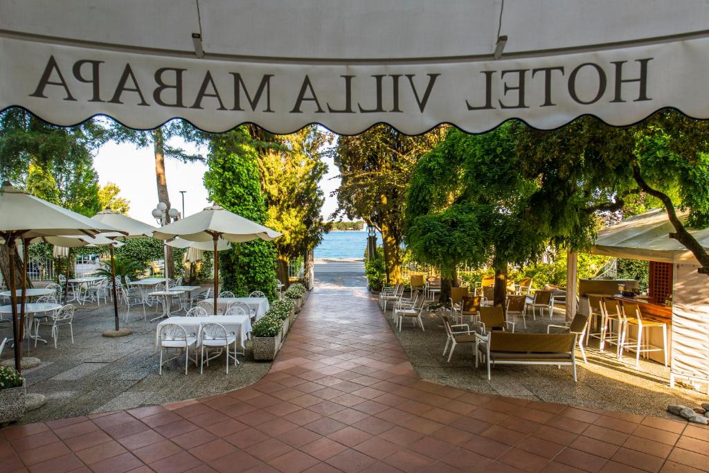 um restaurante com mesas, cadeiras e guarda-sóis em Hotel Villa Mabapa em Lido di Venezia