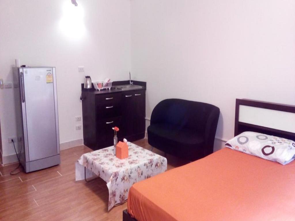 Thung Si KanにあるAsia Don Mueang Bangkok Condominiumの冷蔵庫、椅子、テーブルが備わる客室です。