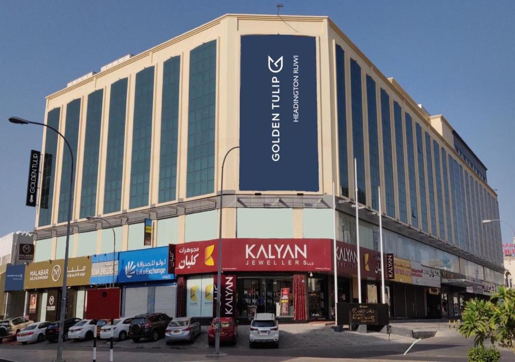 a large building with a sign on the side of it at Golden Tulip Headington in Muscat
