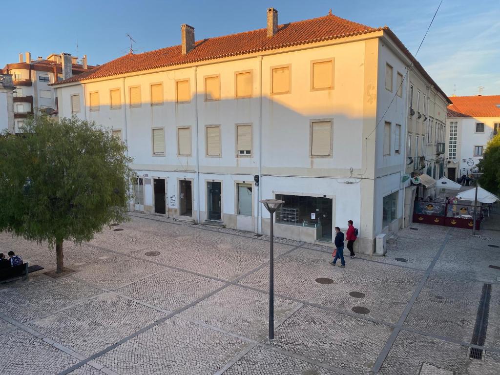 ein großes weißes Gebäude mit Leuten, die davor laufen in der Unterkunft Casa Mouzinho de Albuquerque in Ourém