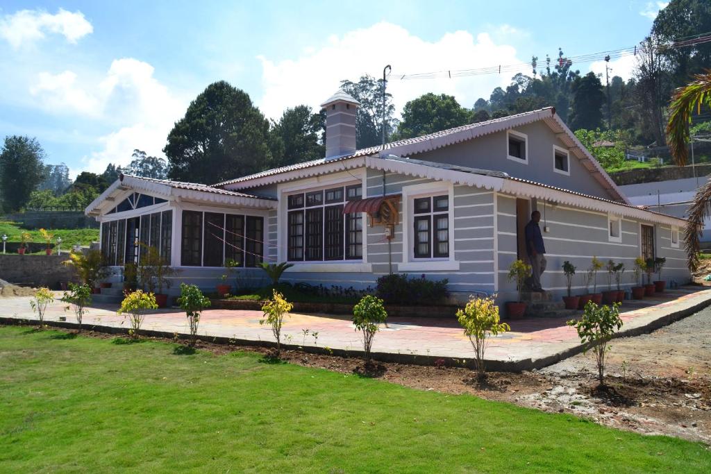ein Haus mit einem Rasen davor in der Unterkunft HILLINGTON COTTAGE in Kodaikanal