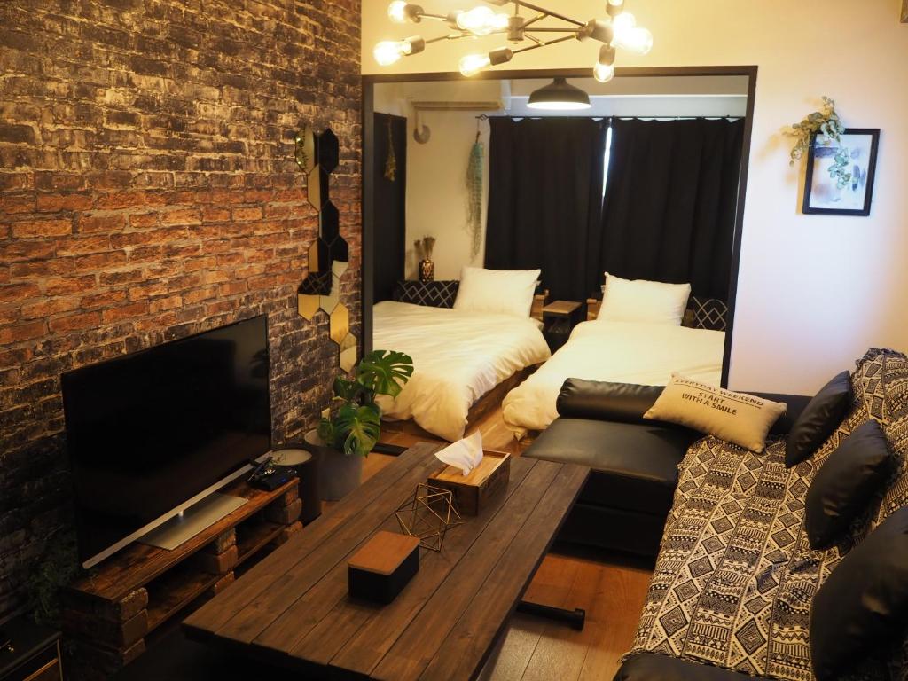 een woonkamer met een bank en een tv en een bakstenen muur bij HOTEL THE SPACE in Tokyo