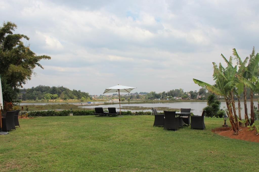 a table and chairs with an umbrella and a river at Riviera Garden in Antananarivo