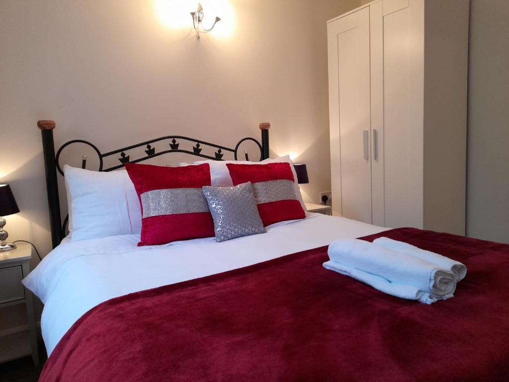 a bedroom with a large bed with red and white pillows at Lucea Cottage in Craven Arms