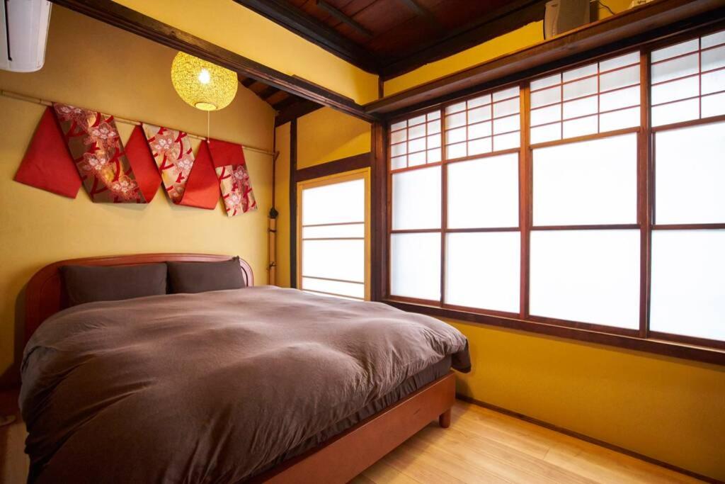 een slaapkamer met een bed in een kamer met ramen bij Koke-an in Kyoto
