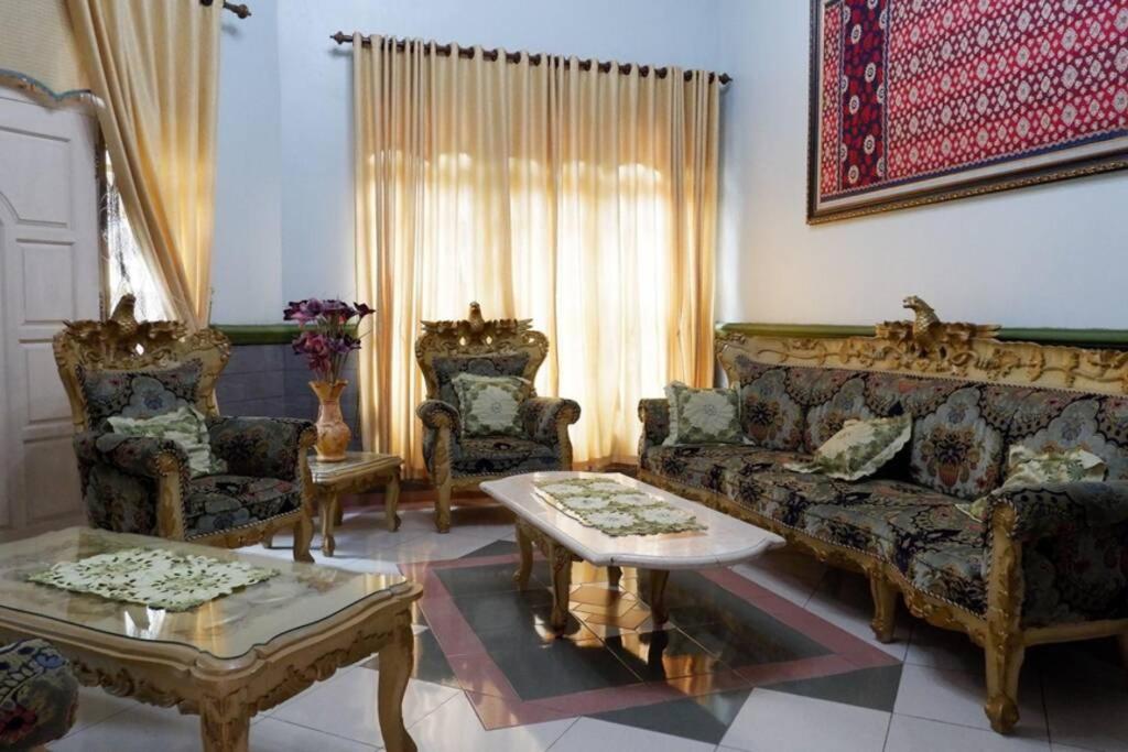 a living room with a couch and two chairs and a table at Samba Homestay in Kedaton