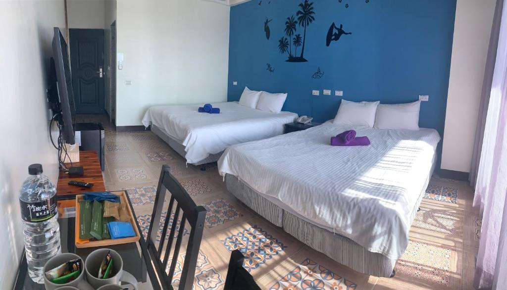 two beds in a room with blue walls at 墾丁秋莊會館 附限量停車位 不保證有位置 無法事先預留 背包房無車位 預訂後記得加Line聯繫 in Hengchun