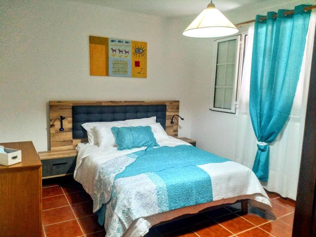 een slaapkamer met een bed en een blauw gordijn bij Refugio das Matas in Porto Santo