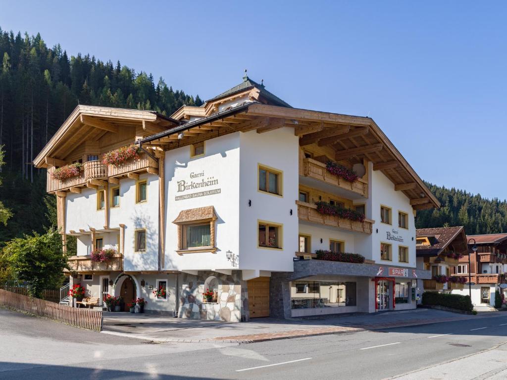 un grand bâtiment blanc sur le côté d'une rue dans l'établissement Garni Birkenheim, à Gerlos