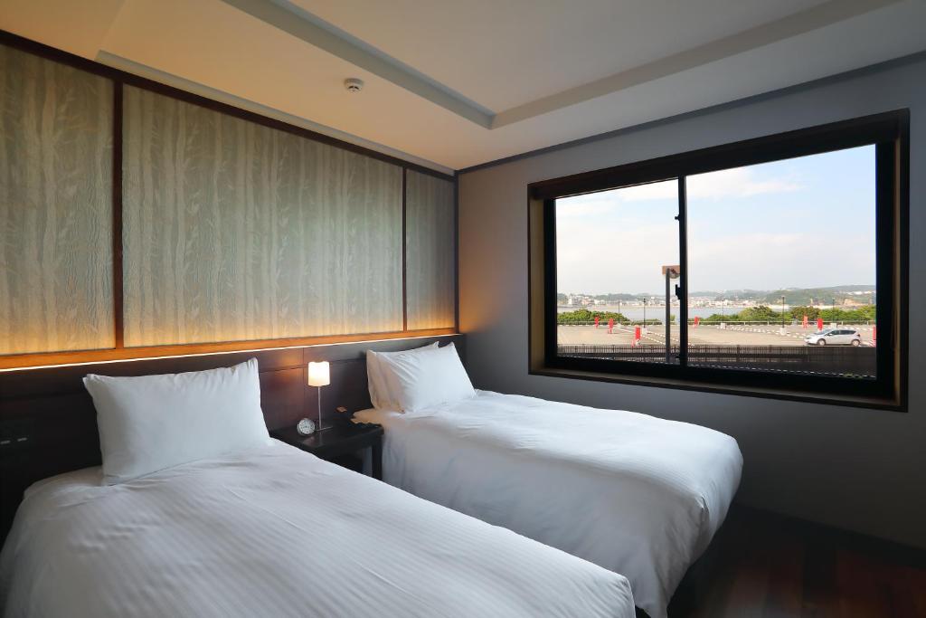 藤沢市にあるEnoshima Hotel ーEnoshima Island Spa Hotel Buildingーの大きな窓付きの客室で、ベッド2台が備わります。