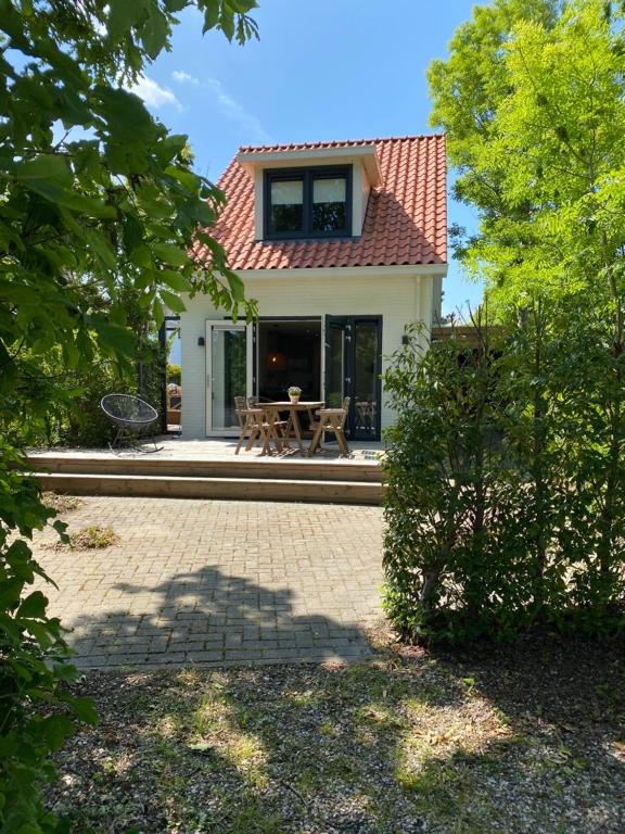 a small white house with a table in front of it at Hello Zeeland - Vakantiehuis Duinenburg 22A in Domburg