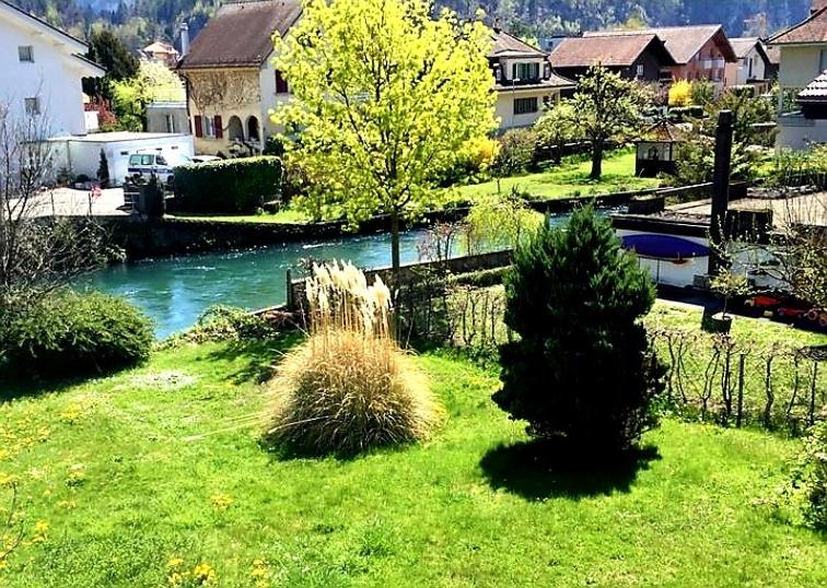 a view of a yard with a river and houses at Bahnhof West Apartments in Interlaken