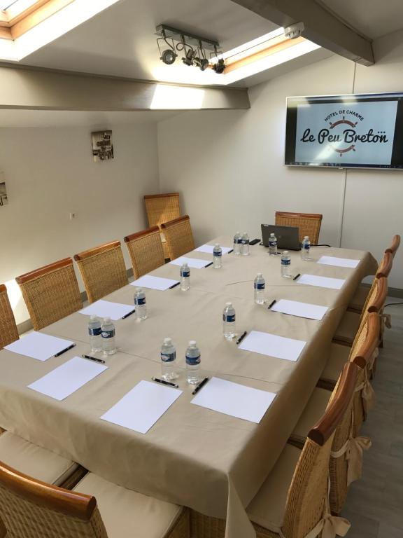 a long table in a room with chairs and a projector at Hôtel Le Peu Breton in Sainte-Marie-de-Ré