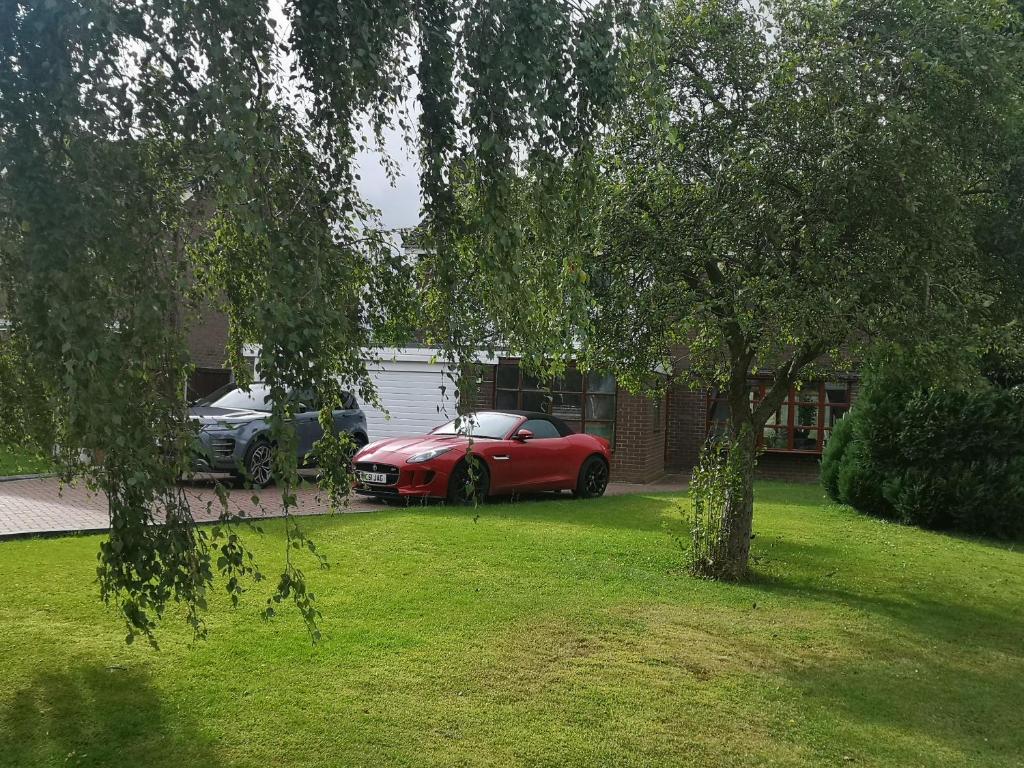 a red car parked in a yard next to a house at Almost Heaven in Acton Trussell