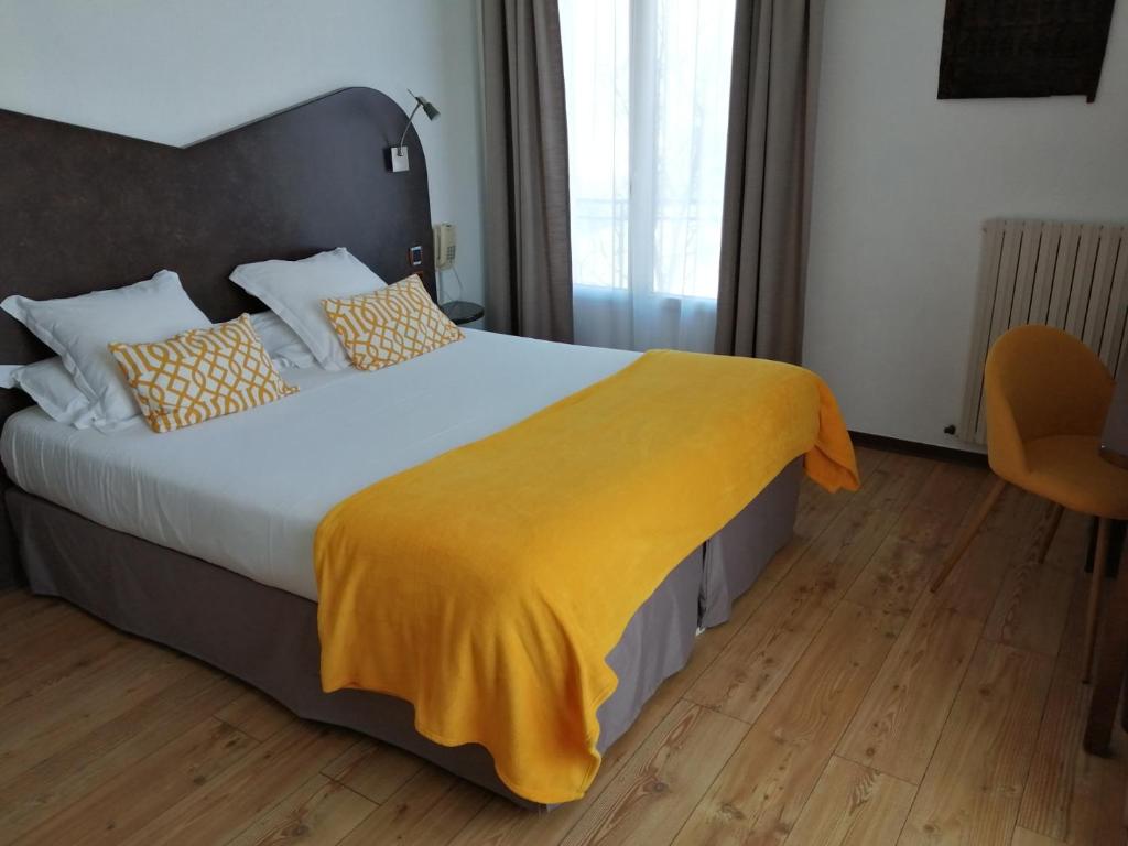 a bedroom with a large bed with a yellow blanket at Hôtel L&#39;Iroko The Originals City in Aix-les-Bains
