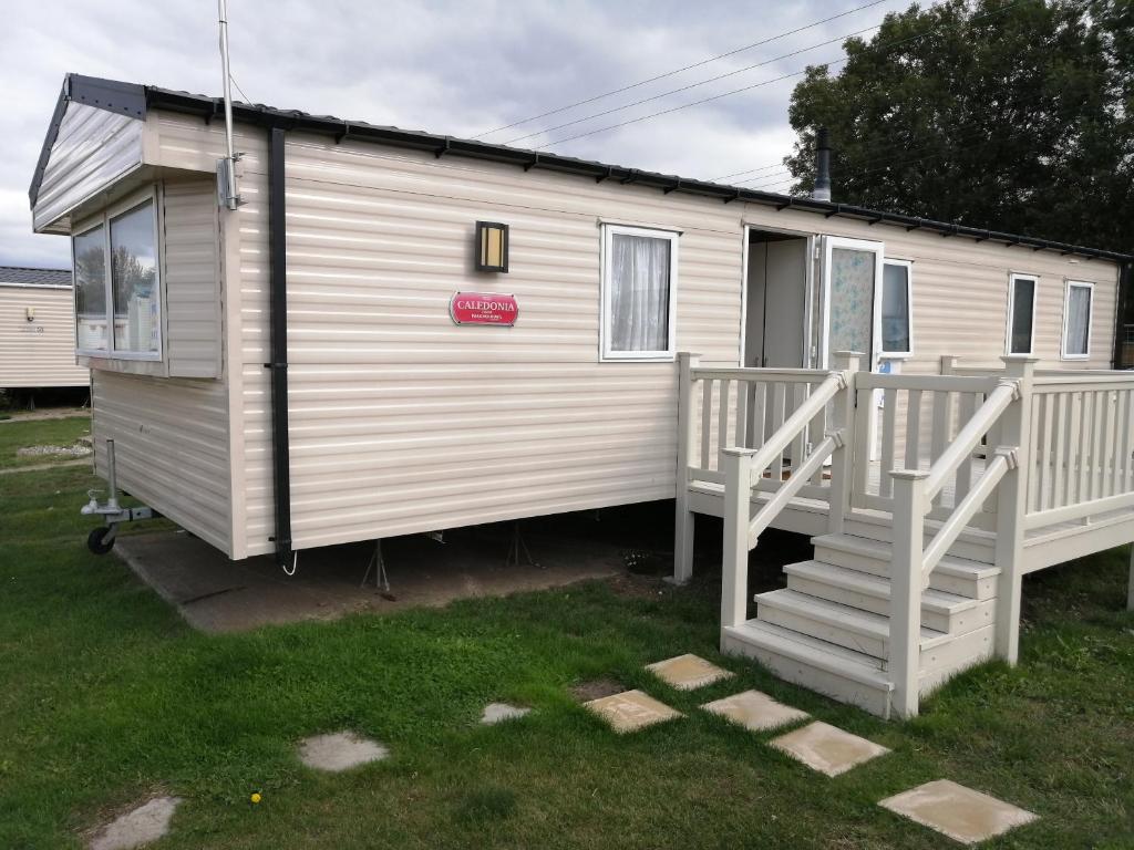 a white tiny house with a porch and stairs at 617 seawick in Jaywick Sands
