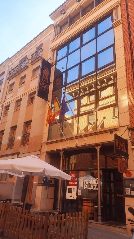 a building with two flags and an umbrella in front of it at Hotel Teruel Plaza in Teruel