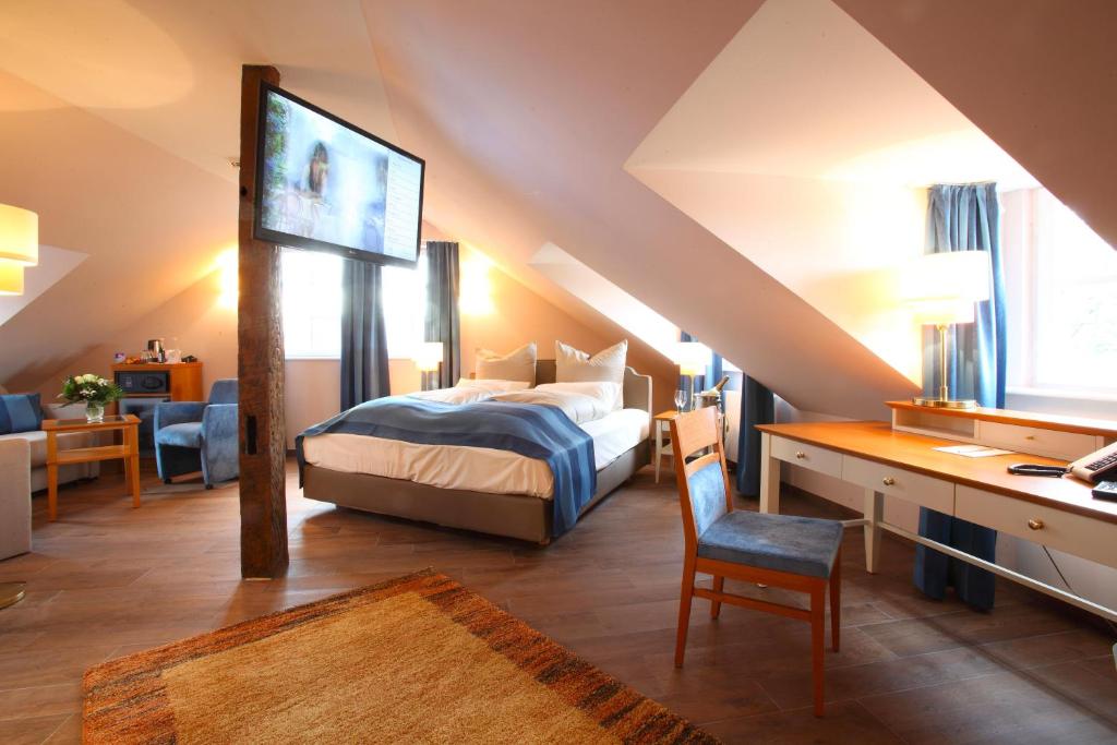 a bedroom with a bed and a desk with a tv at Hotel MainChateau in Seligenstadt