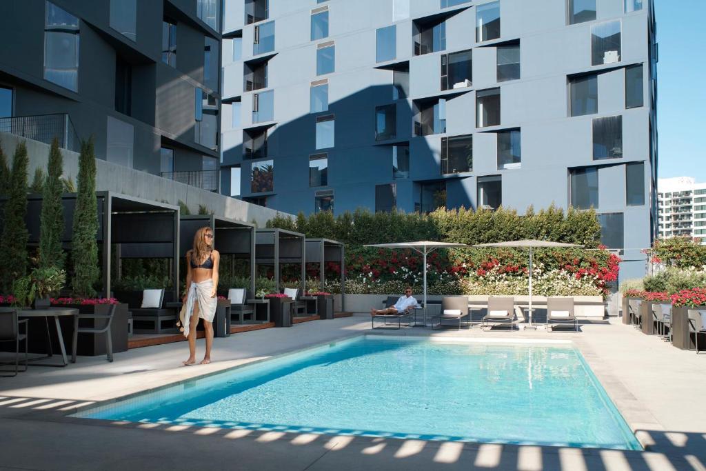 a woman standing next to a swimming pool in a building at AKA West Hollywood, Serviced Apartment Residences in Los Angeles