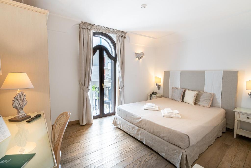 a bedroom with a bed and a desk and a window at Covo dei Saraceni in Polignano a Mare