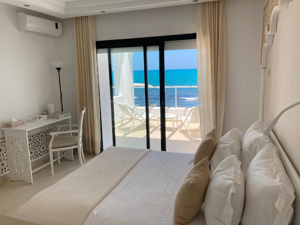 a bedroom with a bed and a view of the ocean at Dar Corniche La Marsa (Adults Only) in La Marsa