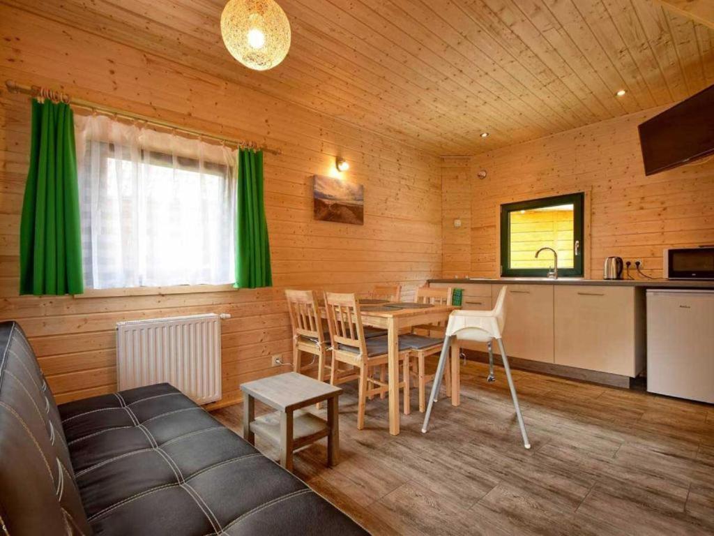 a living room with a table and a kitchen at Zielone Domki in Pobierowo
