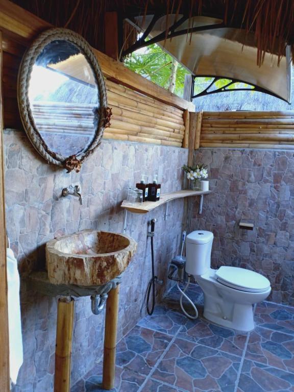 a bathroom with a sink and a toilet and a mirror at Mario Hotel and Cafe in Weetebula