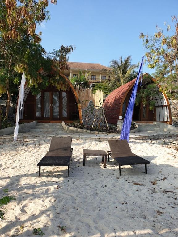 two chairs and an umbrella on the beach at Mario Hotel and Cafe in Weetebula