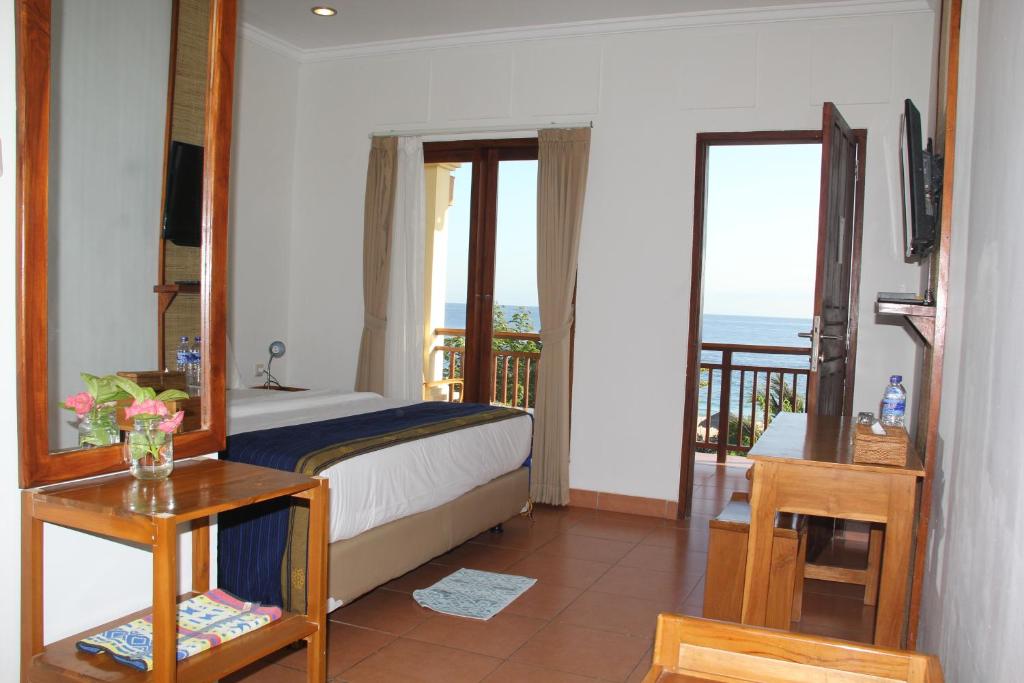 a bedroom with a bed and a balcony with the ocean at Mario Hotel and Cafe in Weetebula