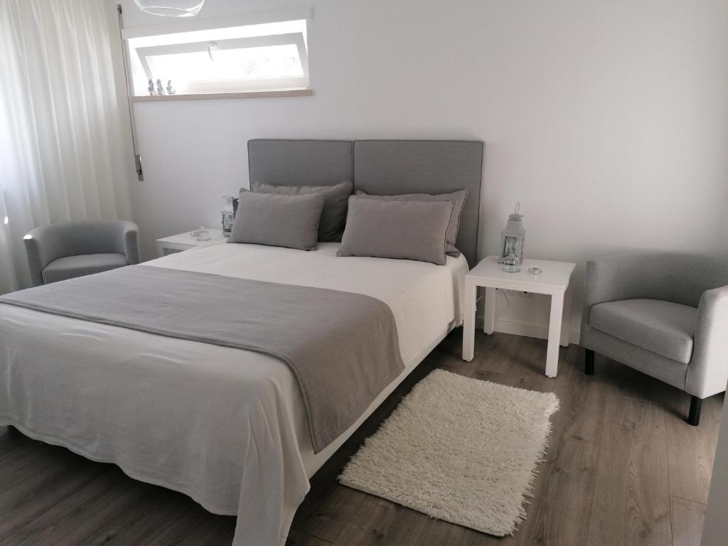 - une chambre avec un grand lit blanc et une chaise dans l'établissement Silver Home, à Nazaré