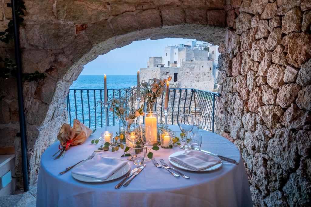 a table with a blue table cloth with a view of the ocean at Covo dei Saraceni in Polignano a Mare