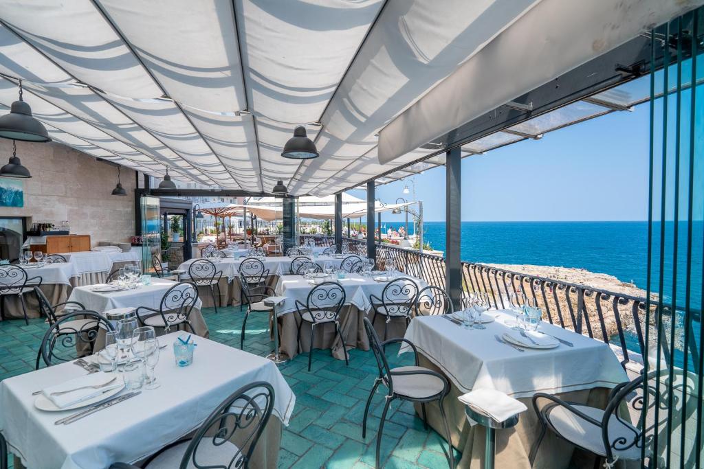 a restaurant with white tables and chairs and the ocean at Covo dei Saraceni in Polignano a Mare