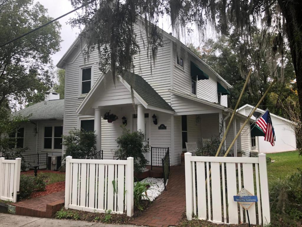 a white house with a white fence and an american flag at Ardendales in Brooksville