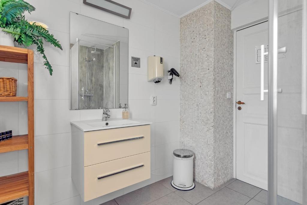 a white bathroom with a sink and a mirror at Guesthouse Vatnsholt in Vatnsholt