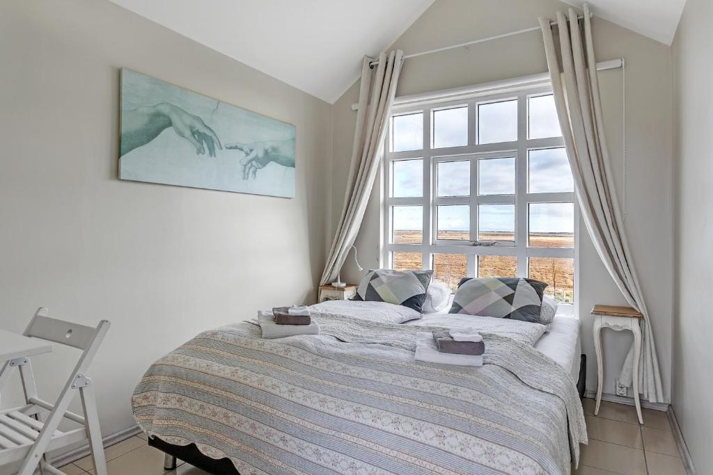 a bedroom with a bed and a large window at Guesthouse Vatnsholt in Vatnsholt