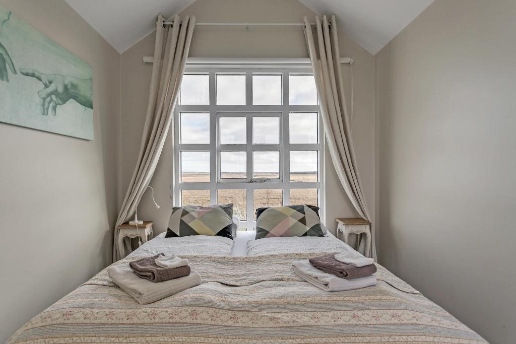 a bed in a bedroom with a large window at Guesthouse Vatnsholt in Vatnsholt